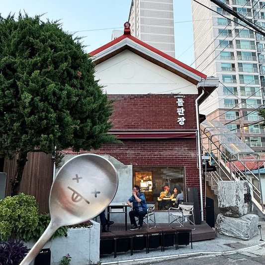 A spoon with a cute expression is taking a picture in front of the restaurant.