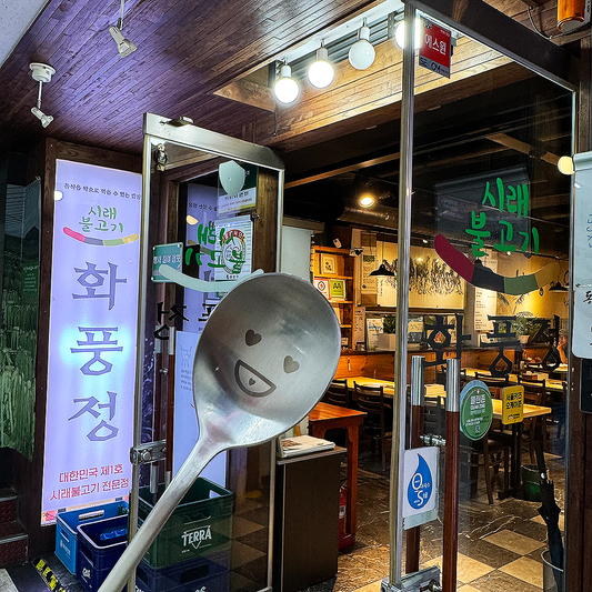 In front of the bulgogi restaurant, there's a spoon shaped like a heart face