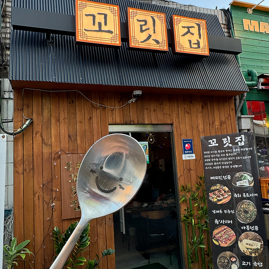 In front of the Kkorijip restaurant sign in Dongmyo, Seoul, there's a smiling spoon.