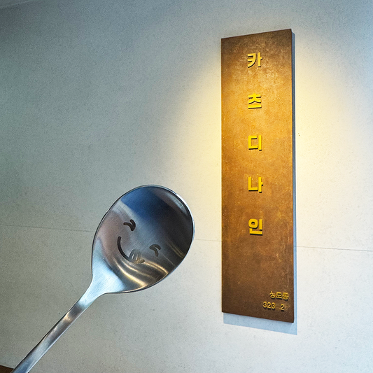 In front of the signboard, there is a spoon with a cute expression.