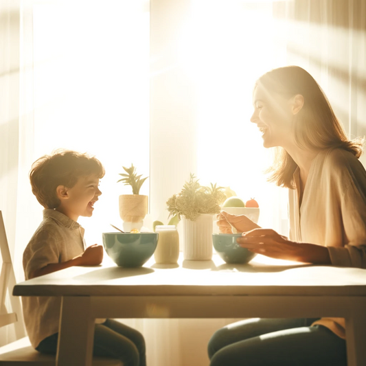 A mother and child are smiling brightly while enjoying a light meal at the table.