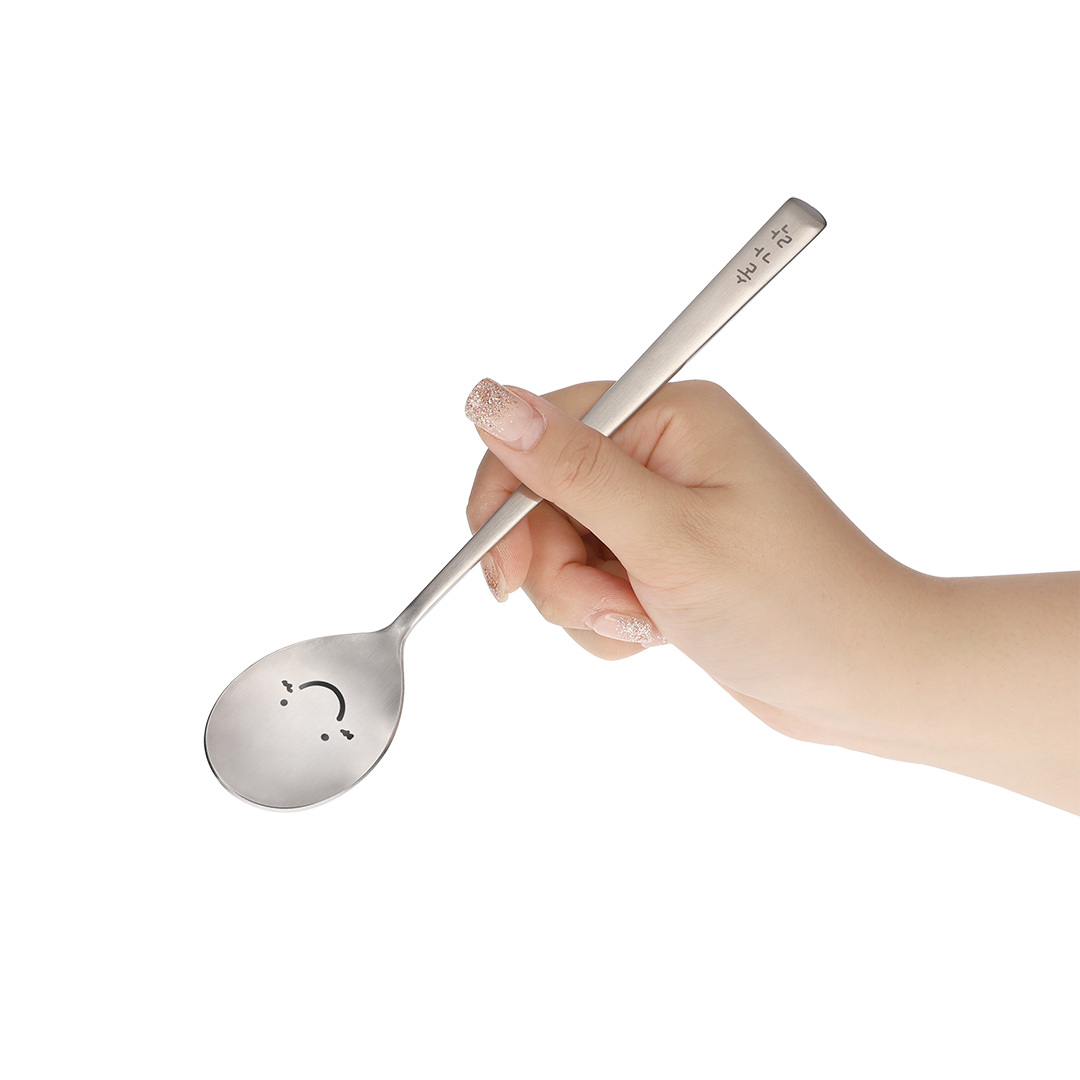 The spoon is held by hand at an angle that shows its happy face.
