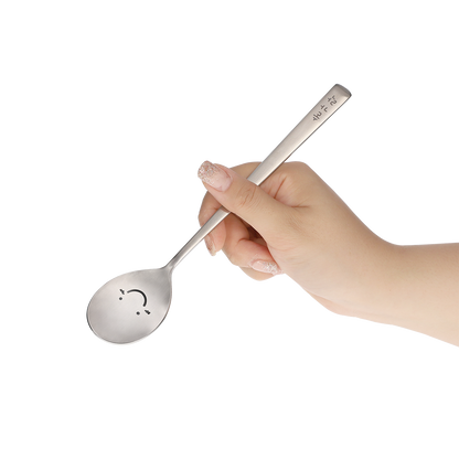 The spoon is held by hand at an angle that shows its happy face.