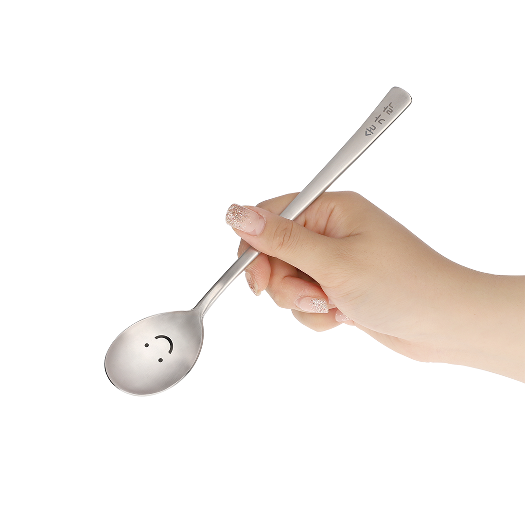 The spoon is held by hand at an angle that shows its smile face.