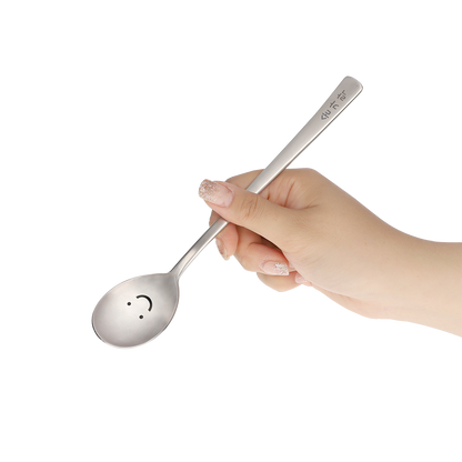 The spoon is held by hand at an angle that shows its smile face.