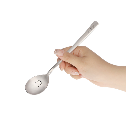 The spoon is held by hand at an angle that shows its smile face.