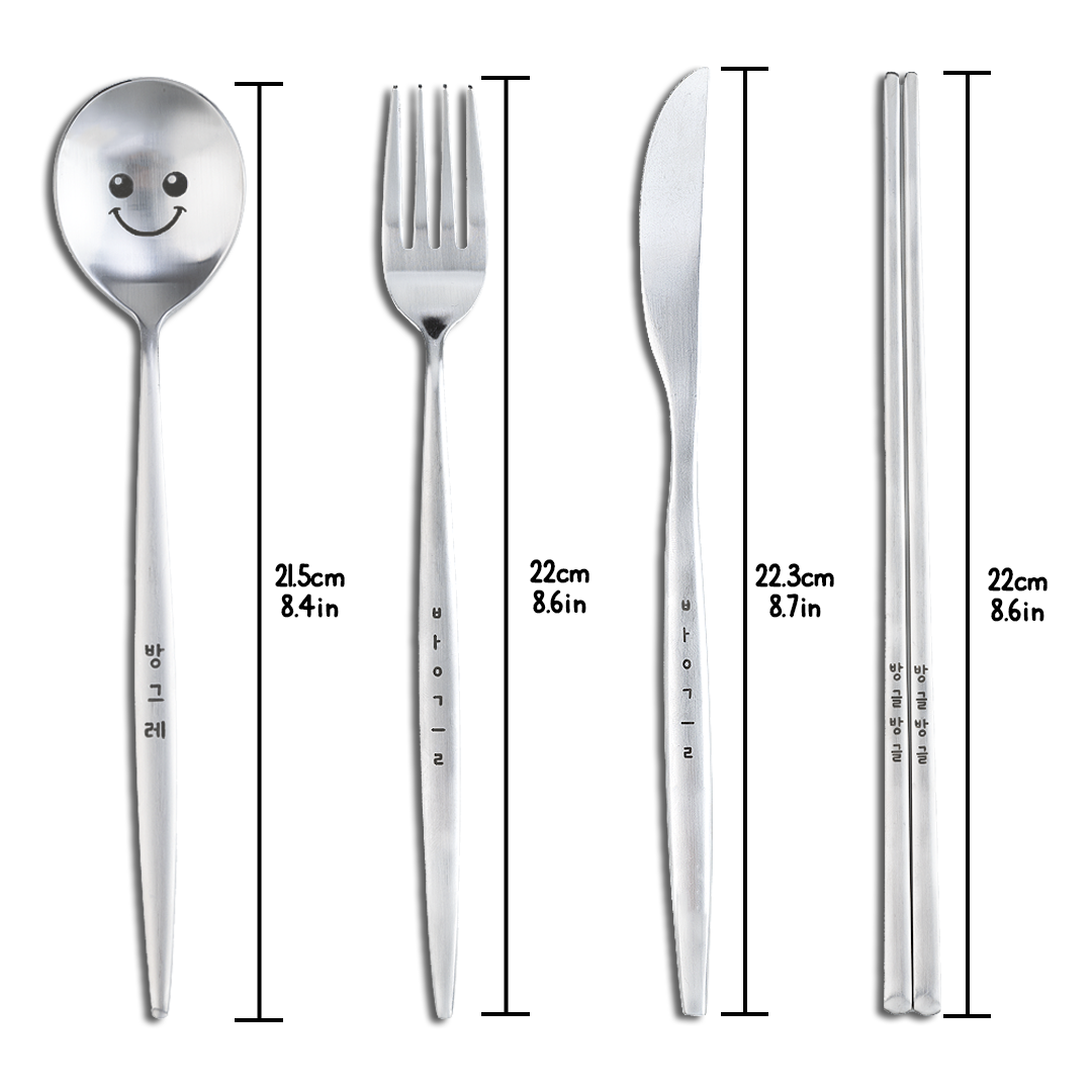 A spoon with a cute face drawn on it, chopsticks with Korean characters on the handle, a fork, and a knife.
