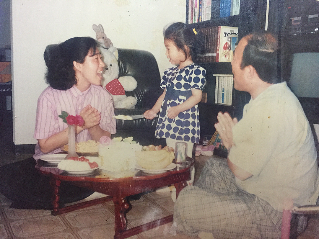 A young girl's parents are singing the birthday song to her on her birthday.